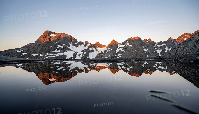 Rocky mountain peaks reflected in a small pond, mountain landscape with alpenglow at sunrise, at the Trollfjord Hytta, at the Trollfjord, Lofoten and Vesterålen, Nordland, Norway, Europe