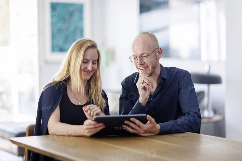 Symbolic photo. A woman and a man sit together at a table with a tablet and talk. Berlin, 13.08.2024