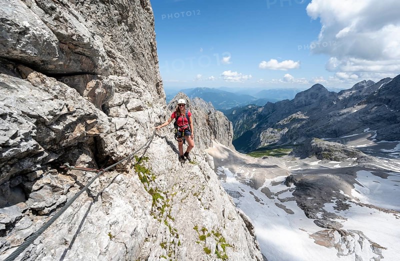 Mountaineer with helmet in a secured via ferrata, Zugspitz via ferrata, ascent to the Zugspitze, view of mountain basin with snowfield of the Höllentalferner and Höllental, Wetterstein range, Bavaria, Germany, Europe