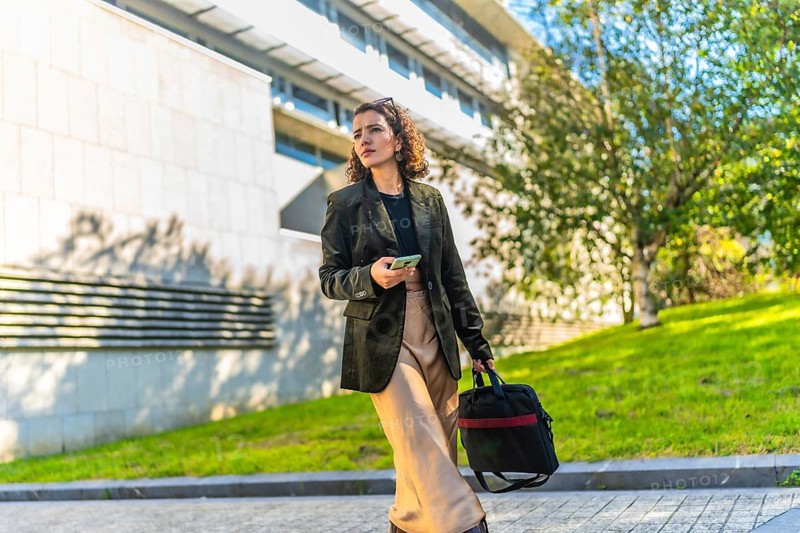 Horizontal photo with copy space of a modern arab businesswoman using mobile walking along the city