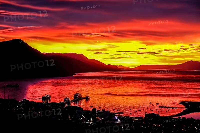 Ushuaia, Tierra del Fuego, Argentina, Glowing red sunrise over the Beagle Channel, the Beagle Channel is a natural waterway at the southern tip of South America that connects the Atlantic Ocean with the Pacific Ocean. Ushuaia is the southernmost city in the world, the end of the world. Behind mountain range on the island of Navarino in Chile, Dientes de Navarino, South America