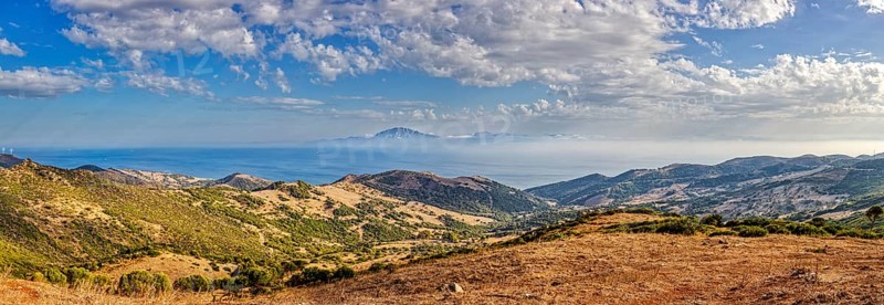 Panorama of a wide hilly landscape with a view of the sea, near Tarifa, view to Morocco
