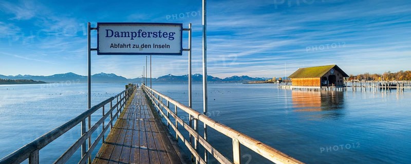 Steamer jetty and boathouse on Lake Chiemsee in autumn in the morning light, behind the Chiemgau Alps, Chiemgau, Bavaria, Germany, Europe