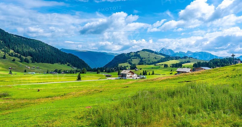 Breathtaking summer scenery in alpe di siusi, dolomites, italy, showcasing lush green meadows, rolling hills, traditional houses, and a vibrant blue sky