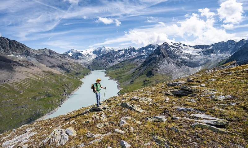 Mountaineer on the summit of Mont de la Blana, view of a blue mountain lake, Lac des Dix reservoir, behind mountain peak Mont Blanc de Cheilon with glacier, Hérménence, Valais Alps, Valais, Switzerland, Europe