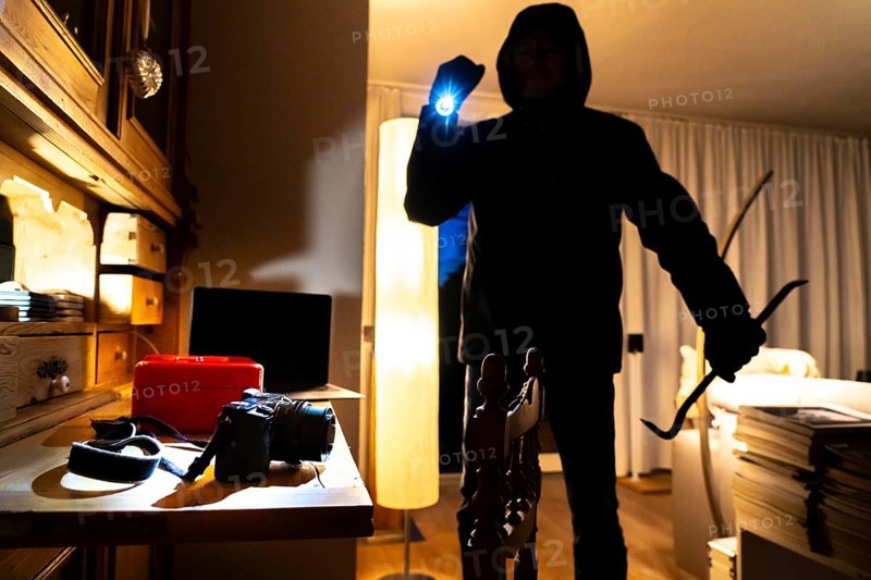 Symbolic image of a burglary, perpetrator has broken into a flat from the garden side and is looking for loot, cash box, valuables, money, technology