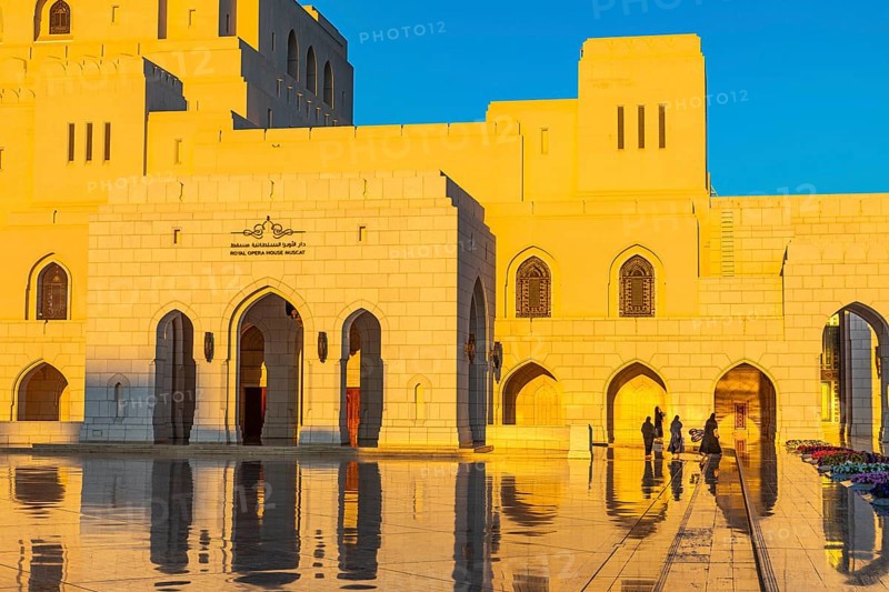Local woman in traditional dress stroll across the main square of the Royal Opera in the evening light, Muscat, Arabian Peninsula, Sultanate of Oman
