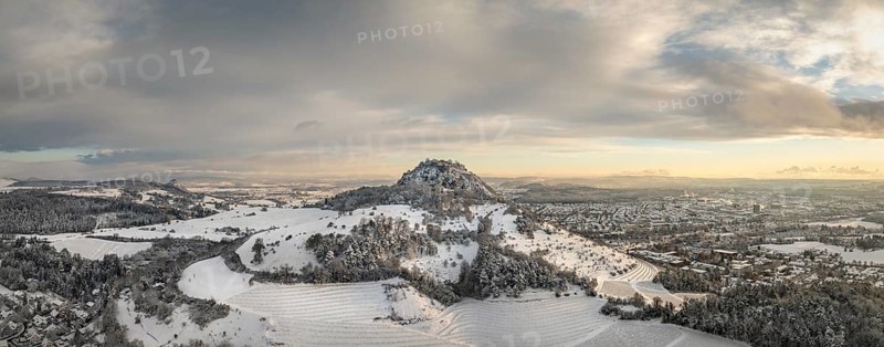 Aerial view, panorama of the snow-covered Hegau volcano Hohentwiel with Germany's largest castle ruins at sunrise, in front of it Germany's highest vineyard, the Elisabethenberg at 505 metres above sea level, on the right the town of Singen, on the left on the horizon the neighbouring Hegau volcano Hohenkrähen, district of Constance, Baden-Württemberg, Germany, Europe