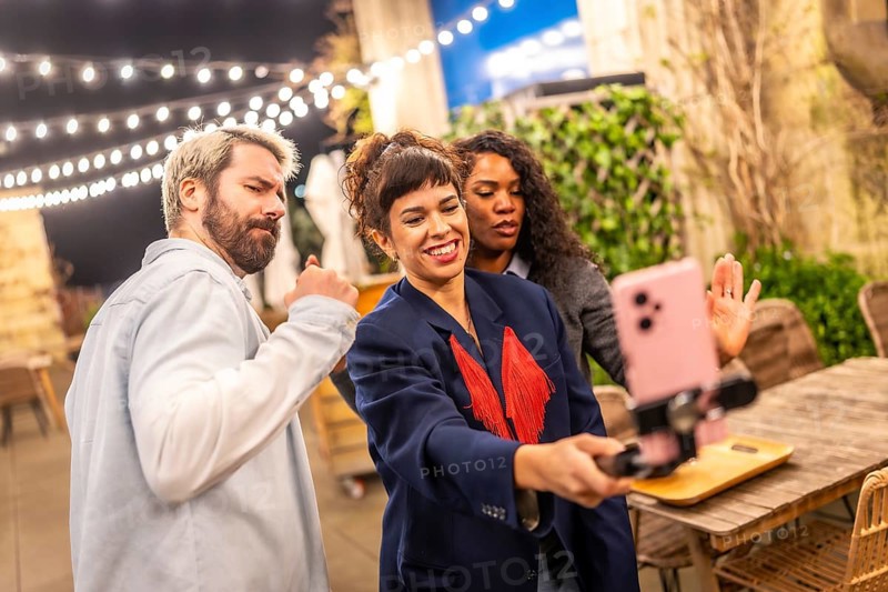 Female caucasian vlogger streaming online using the smartphone in a night party with friends