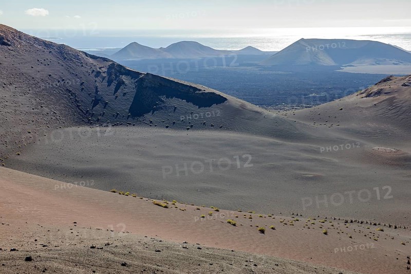 Volcanic landscape on the Canary Island of Lanzarote in Timanfaya National Park, Lnzarote, in the background on the Atlantic Ocean horizon, Canary Islands, Spain, Europe