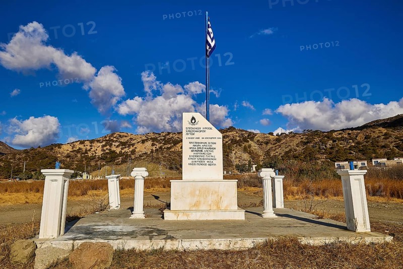 Greek monument with flag under clear blue sky and mountainous background landscape, Christopher Litos Monument, Pigadia, town and harbour, Pigadia Bay, main town, Karpathos, Dodecanese, Greek Islands, Greece, Europe