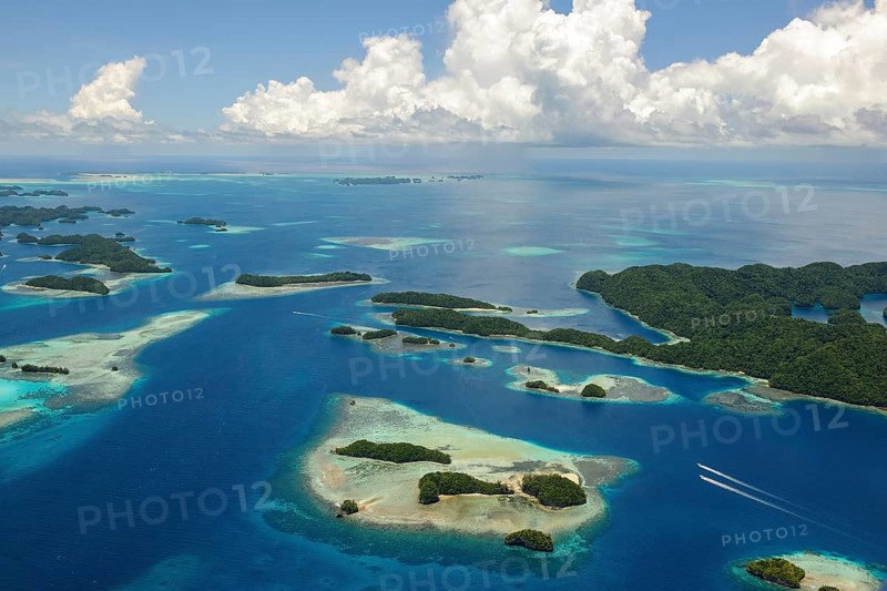 Aerial view bird's eye view of UNESCO cultural heritage natural heritage Rock Islands islands in southern lagoon of island paradise island state Palau in the Pacific West Pacific, on the horizon white clouds cumulus in blue sky, Republic of Palau, Micronesia, Australia, Oceania