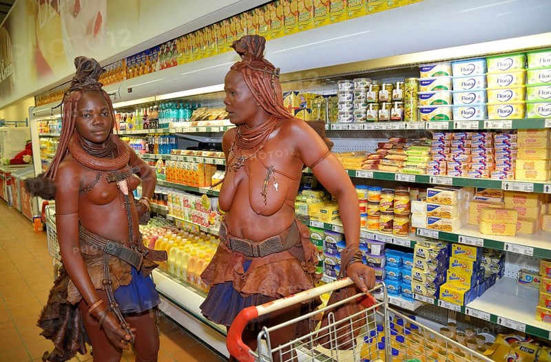 Traditionally dressed Himba women standing in front of the refrigerated section of a supermarket, Opuwo, Kaokoland, Kunene, Namibia, Africa