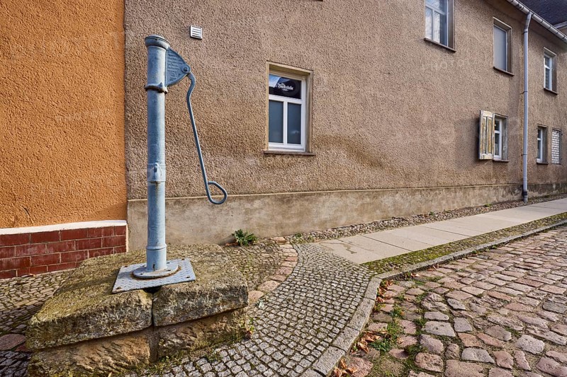 Historic pump, hand pump, pavement, cobblestones, facade with windows, Mühlberg Elbe, Elbe-Elster district, Brandenburg, Germany, Europe
