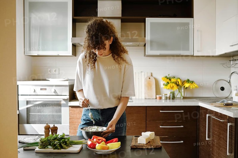 Woman makes stuffing for bell peppers in a bowl in the kitchen
