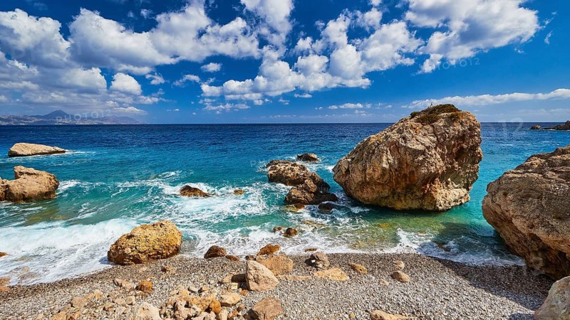 Stony beach with large rocks and gentle waves under a blue sky, Kato Lakkos Beach, still almost unspoilt bay, not accessible by car, Kato Lakkos, east coast, Karpathos, Dodecanese, Greek Islands, Greece, Europe