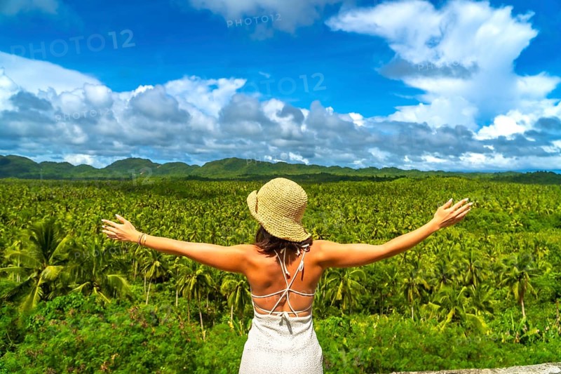 Tourist embracing the stunning view of a vast coconut plantation in siargao island, philippines, enjoying the tropical landscape during a sunny day