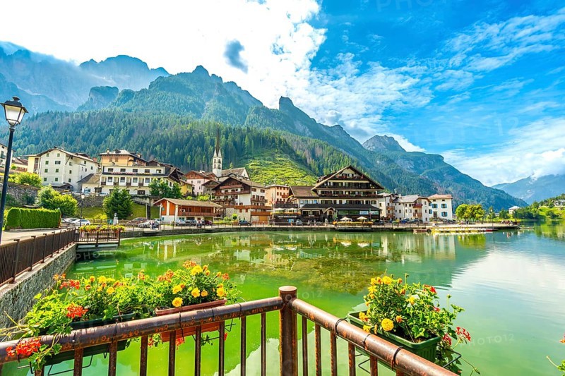 Picturesque village of alleghe reflecting on the lake with the dolomites in the background during a summer day