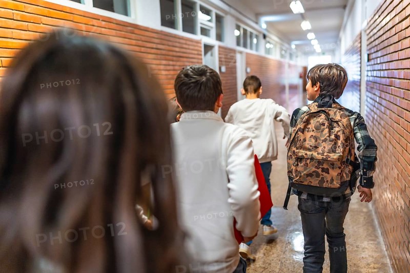 Pupils running down school hallway after class bell rings, eager to get home or to extracurricular activities
