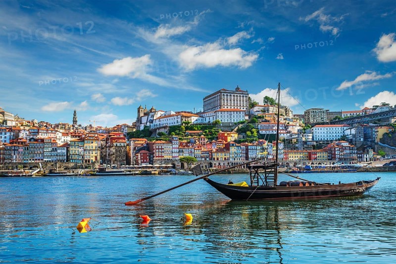 View of Porto city and Douro river with traditional boats with port wine barrels ship from famous tourist viewpoint Marginal de Gaia riverfront. Porto, Vila Nova de Gaia, Portugal, Europe