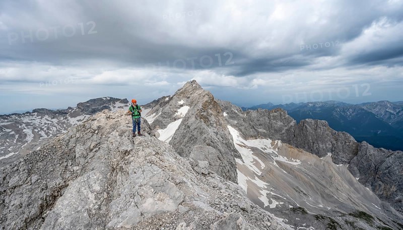 Mountaineer with helmet on a narrow rocky ridge, crossing the Jubiläumsgrat, behind the summit of the Zugspitze, Wetterstein range, Bavaria, Germany, Europe
