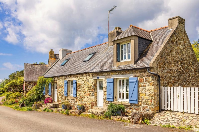 Idyllic old stone cottage by a road in the French countryside with flower pots by the wall on a sunny summer day, Crozon peninsula, Bretagne, France, Europe