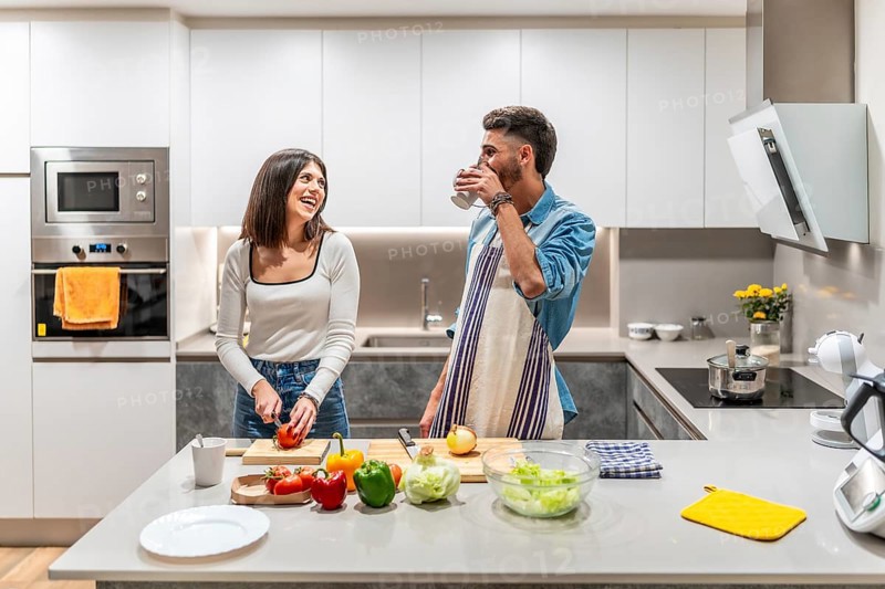 Happy couple preparing a healthy meal of fresh vegetables in their kitchen, enjoying time together and sharing a laugh