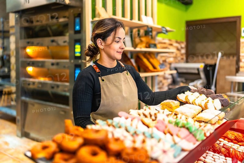 Side view photo with copy space of a latin young friendly woman selling bread and pastries in an artisan bakery