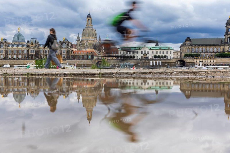 The Dresden silhouette with a cyclist and dark clouds behind the Church of Our Lady is reflected in a puddle on the Elbe cycle path, Elbe cycle path, Dresden, Saxony, Germany, Europe