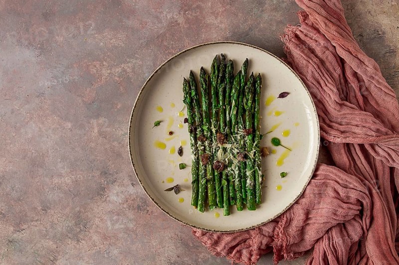 Grilled asparagus, spices and herbs, parmesan cheese, on a beige plate, top view, rustic, no people