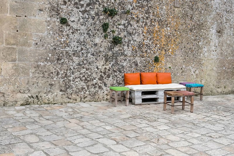 Pallet bench with colourful cushions in front of a high wall, Matera, Basalikata, Italy, Europe
