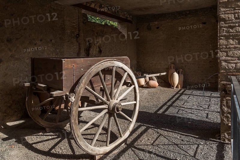 Old wooden cart and ceramic jugs on display inside an unenclosed building at the ancient ruins of Pompeii, Campania region, Italy, Europe