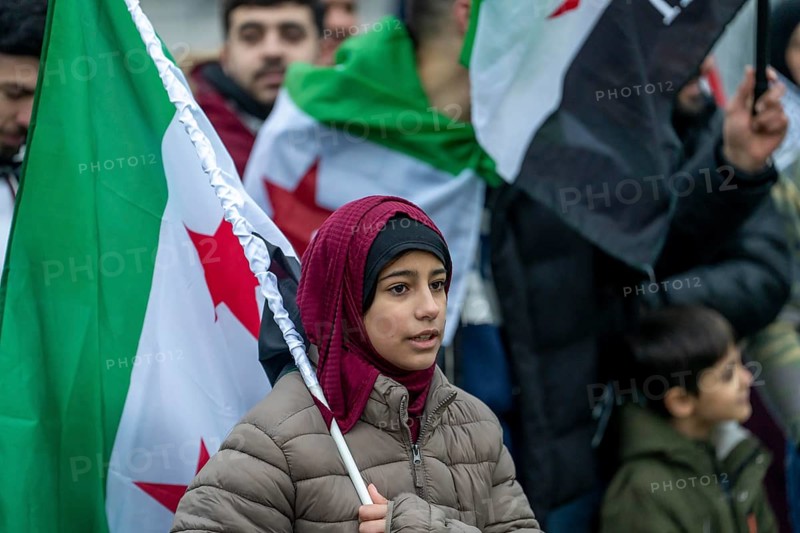Syrian woman celebrate the end of the Assad regime after the change of power in Syria at a rally on the square in front of the main railway station in Duisburg, North Rhine-Westphalia, Germany, Europe