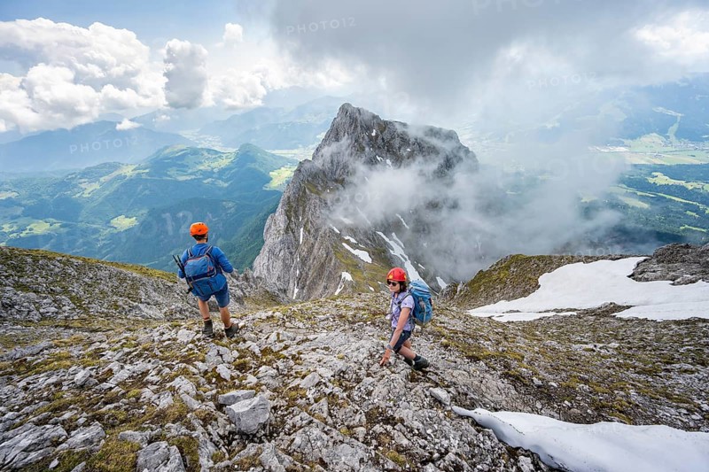 Mountaineer with helmet on a narrow hiking trail, ascent to the Ackerlspitze, clouds moving around the mountains, Wilder Kaiser, Kaiser Mountains, Tyrol, Austria, Europe