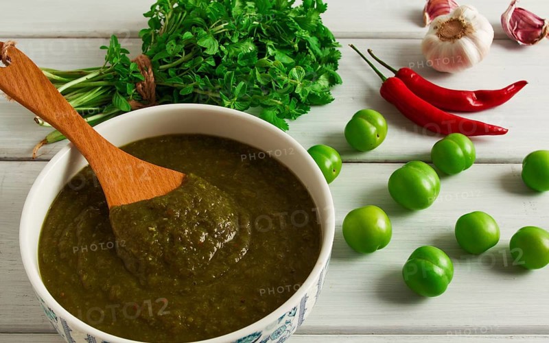 Tkemali sauce, traditional Georgian cuisine, green cherry plum, with ingredients for sauce, cilantro, mint, hot pepper, garlic, on a white wooden table, close-up, rustic, food background, no people, selective focus, sauce, green sauce, tkemali, georgian cuisine, homemade