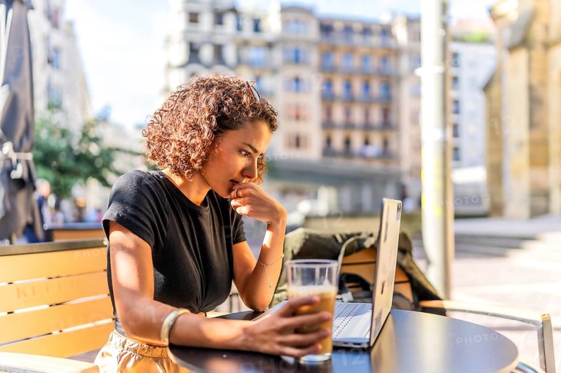 Arab young businesswoman drinking coffee sitting on a terrace working with laptop in the city