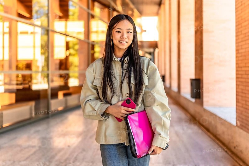 Frontal portrait of a chinese beauty female student standing smiling at camera at the university