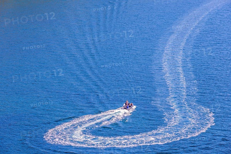 Inflatable boat with people turning on the sea and making wake pattern on the water surface, Crozon peninsula, Bretagne, France, Europe