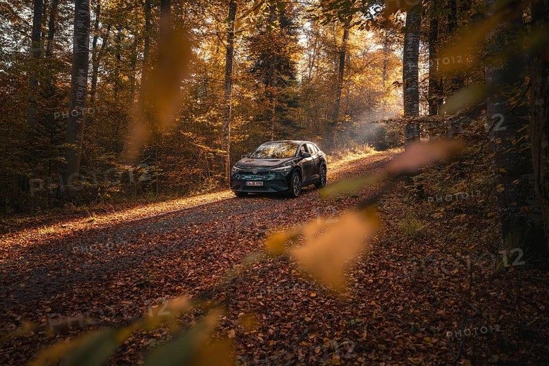 Car driving slowly through a quiet, autumnal forest path in the sunlight, electric car VW ID5, Gechingen, Black Forest, Germany, Europe