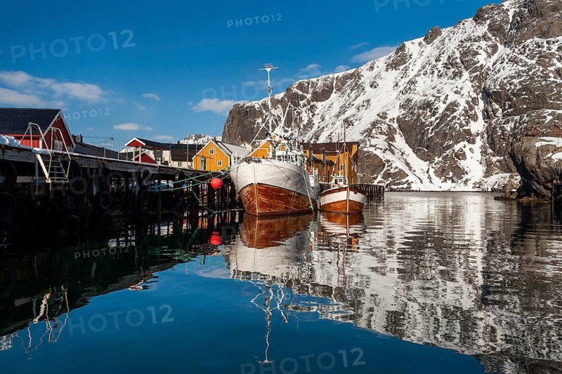 Fishing boats, fishing village with yellow houses in front of snowy mountains, Nusfjord, Flakstadoya or Flakstadøy, Vestvågøya island, Lofoten, Norway, Europe