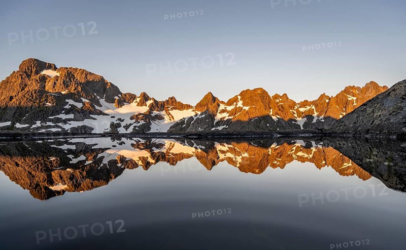 Rocky mountain peaks reflected in a small pond, mountain landscape with alpenglow at sunrise, at the Trollfjord Hytta, at the Trollfjord, Lofoten and Vesterålen, Nordland, Norway, Europe