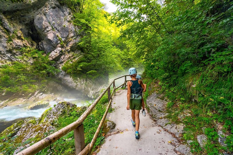 Tourists walking on a pathway along the radovna river in vintgar gorge, enjoying the scenic beauty of the canyon near bled, slovenia