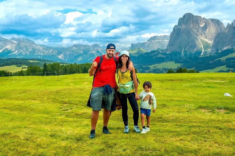 Family enjoying summer vacation hiking in alpe di siusi, with the sciliar mountain in the background