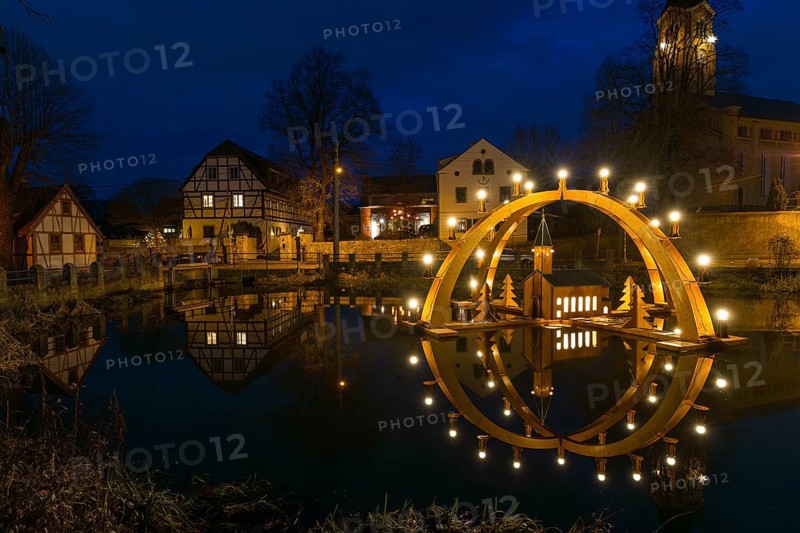 Floating double candle arch from the Ore Mountains with model of the church on the village pond, behind it the village church of Bärnsdorf, Radeburg, Saxony, Germany, Europe