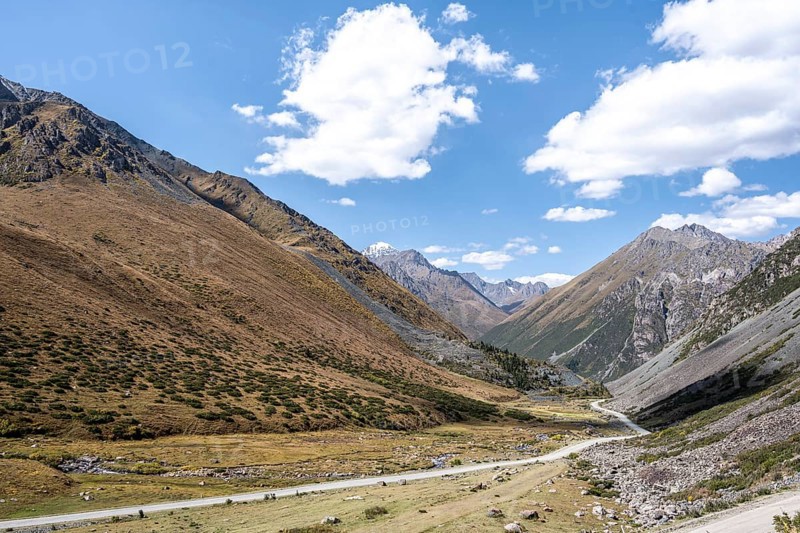 Gravel track in a valley, picturesque mountain landscape with white mountain peaks, Tian Shan Mountains, Issyk-Kul, Kyrgyzstan, Asia