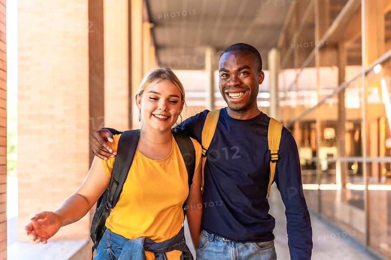 Multi-ethnic caucasian and african friends embracing from shoulder walking along the university