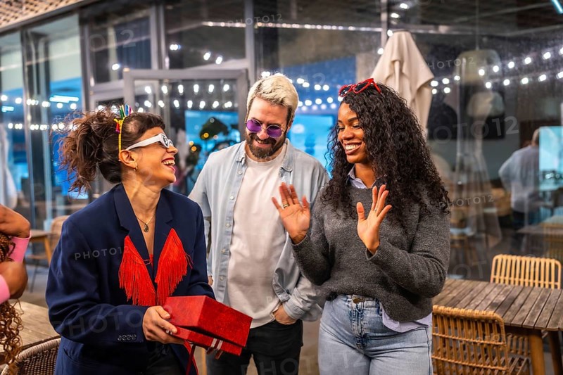 Happy woman receiving birthday gift during night party with friends in a bar