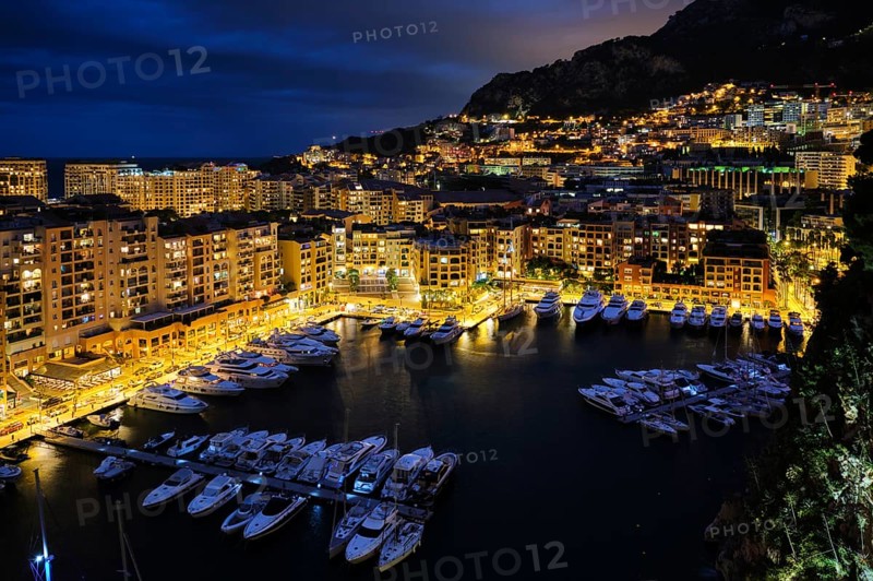 Aerial view of Monaco Monte Carlo harbour and illuminated city skyline in the evening blue hour twilight. Monaco Port night view with luxurious yachts