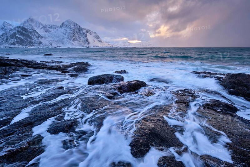 Beach of Norwegian sea on rocky coast in fjord on sunset in winter. Vareid beach, Lofoten islands, Norway, Europe