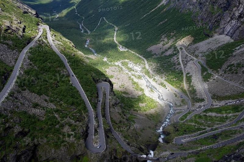 A winding road meanders through a green valley between steep mountains, Trollstigen, Andalsnes, Norway, Europe